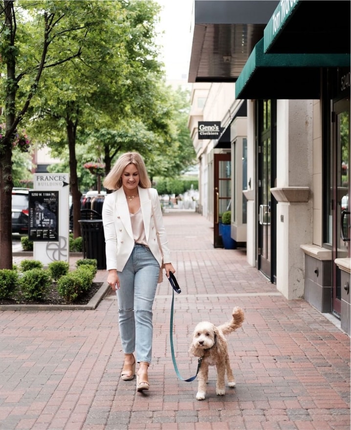 a woman walking a dog down a sidewalk.