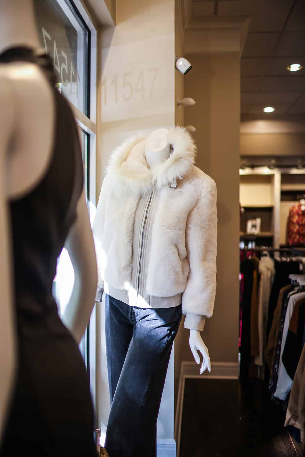 a mannequin wearing a white fur coat in a clothing store.